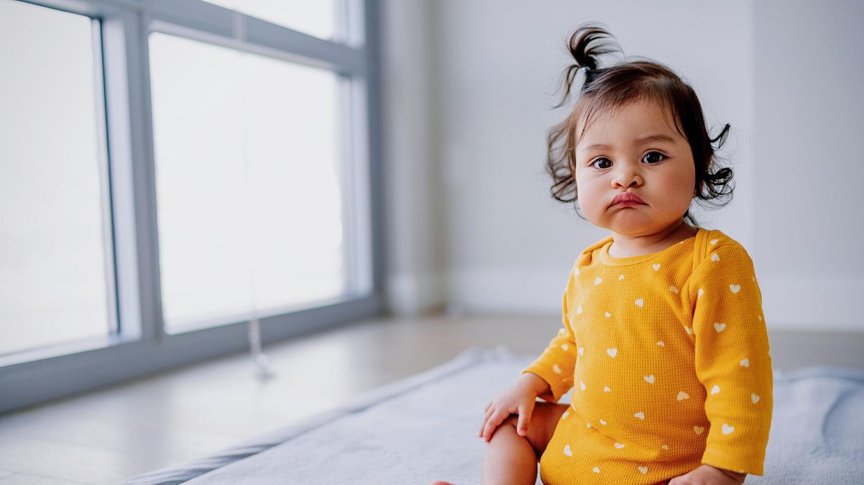 Baby girl wearing a yellow romper.