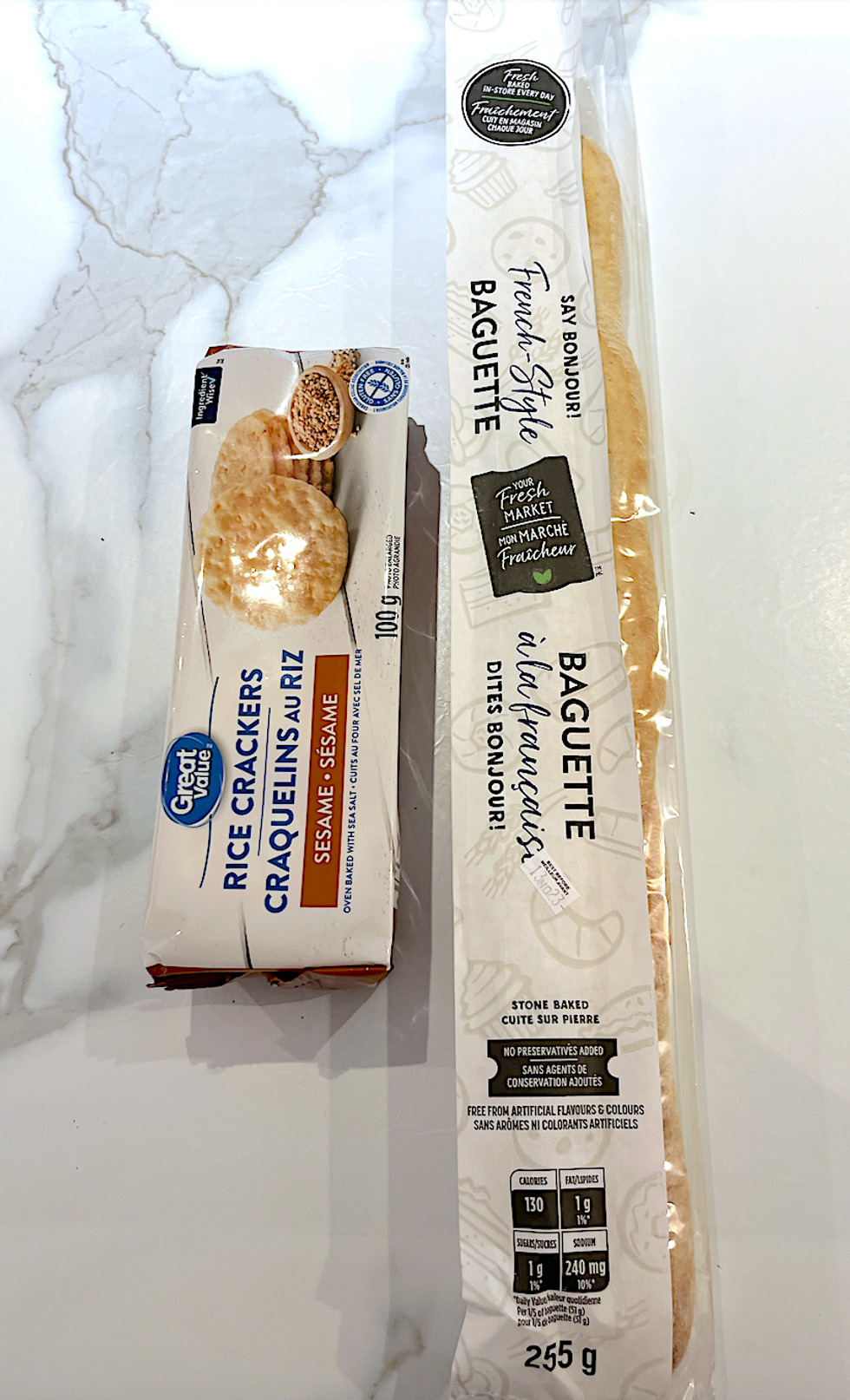 Baguette de pain et craquelins au riz pos\u00e9s sur un comptoir de marbre.