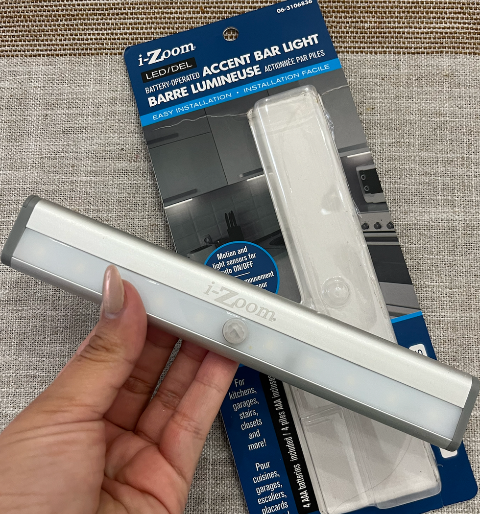 Barre lumineuse tenue dans une main, devant son emballage pos\u00e9 sur une table.