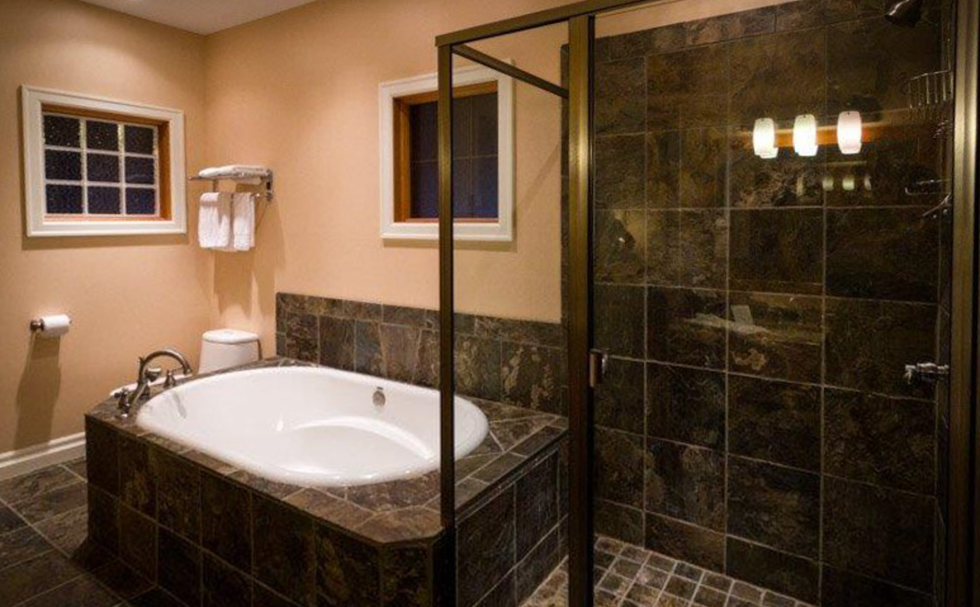 Bathroom with dark marble bathtub and shower.