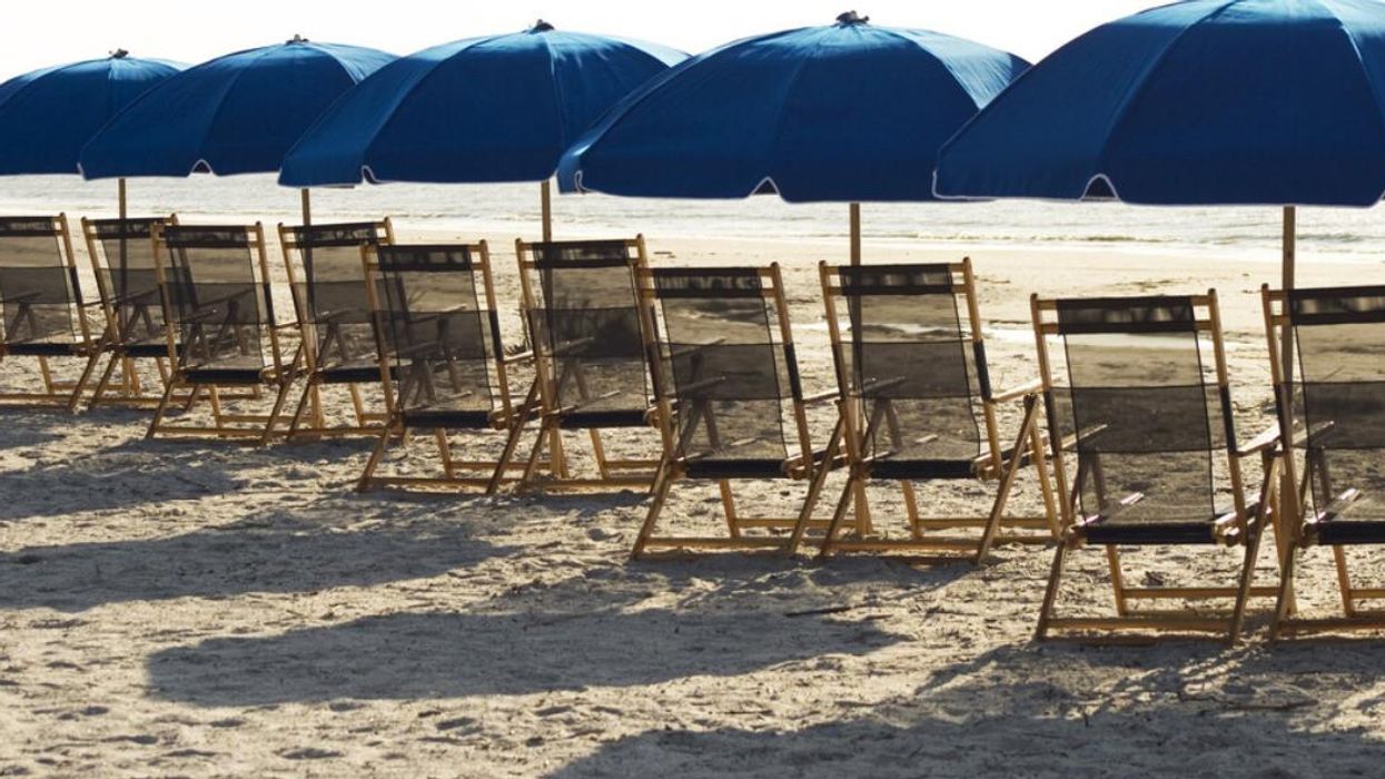 Beach umbrellas and lounge chairs are shown on a sandy beach.