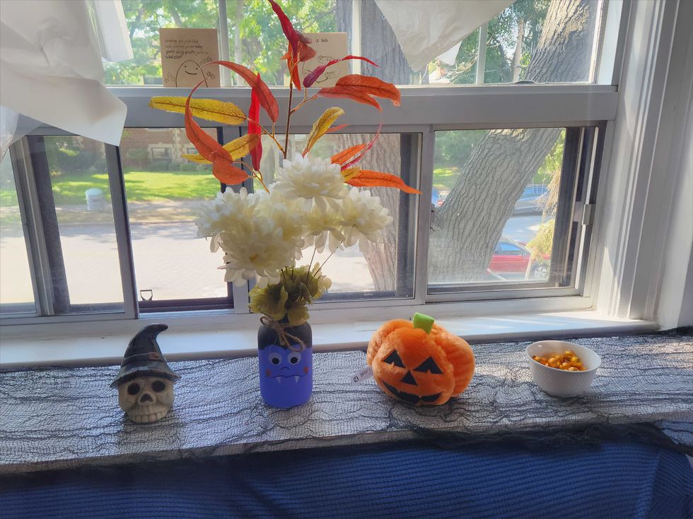Black gauze material, a skeleton head, a monster vase with faux flowers, a plush pumpkin and chocolates in a bowl.