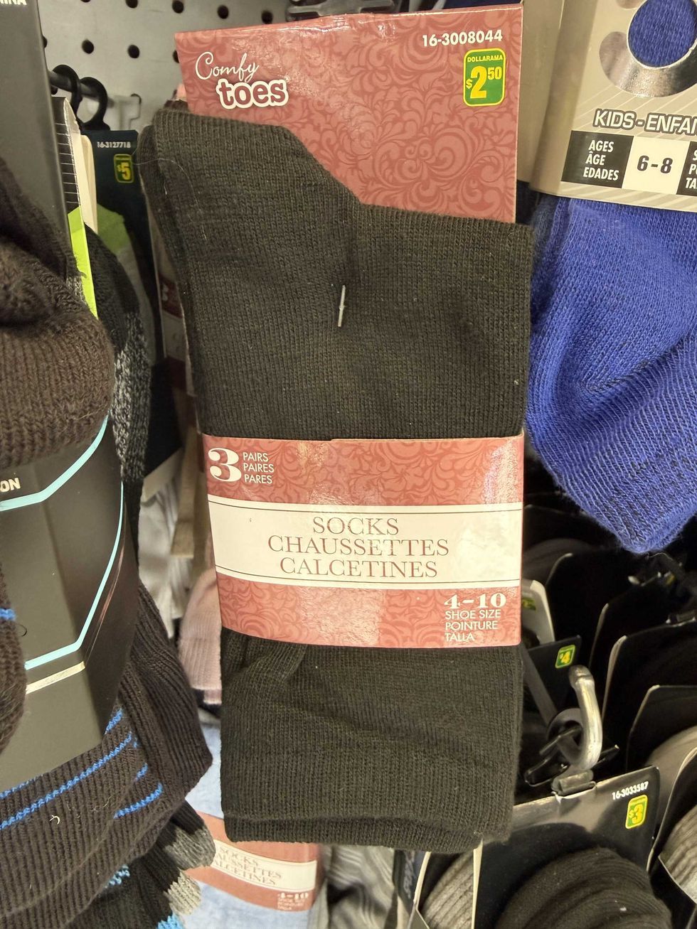 Black socks hanging on a store shelf with a red and white label on the front that says 3 pairs of socks.