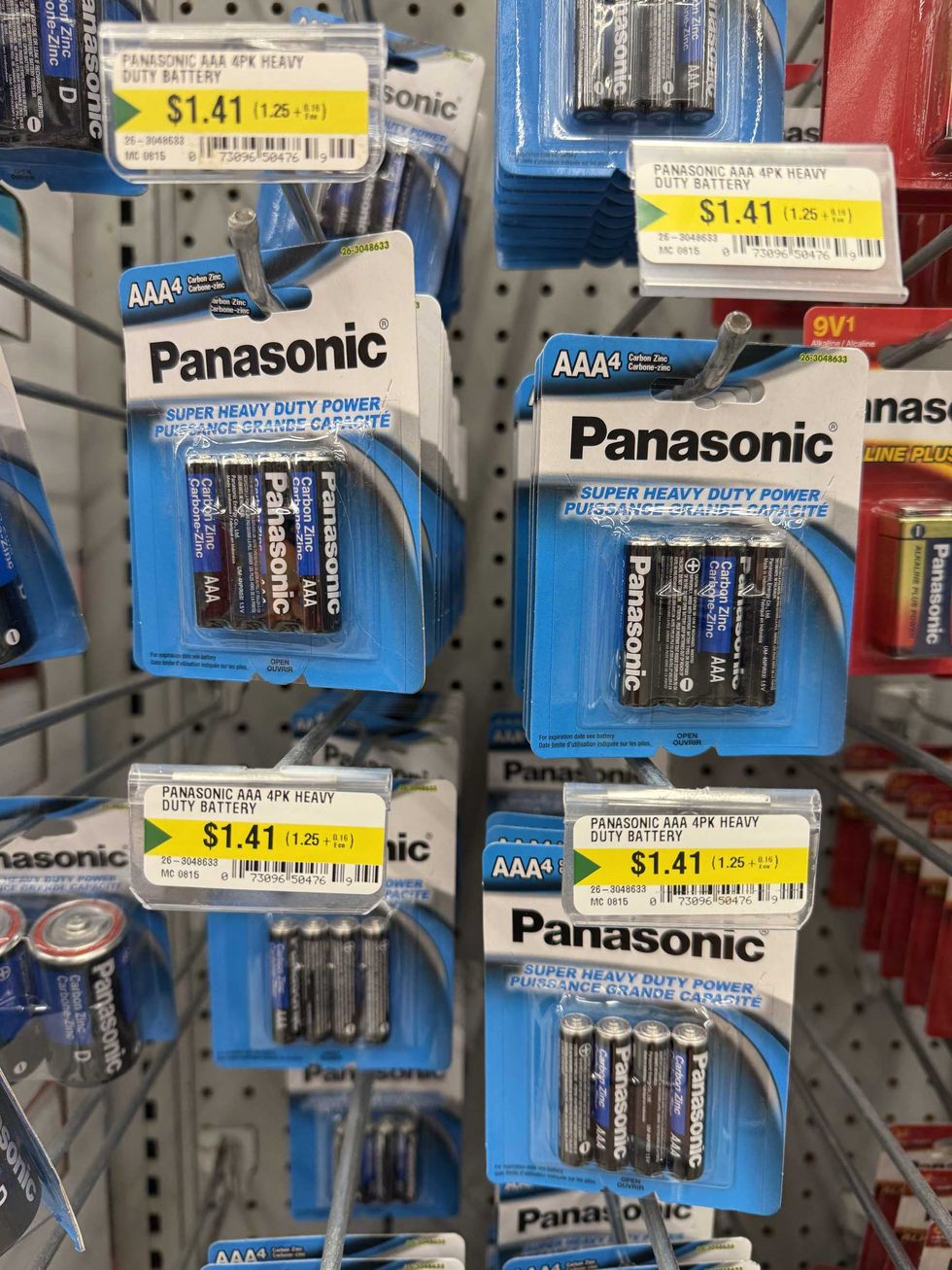 Blue, white and black packages filled with batteries hanging on a store shelf.