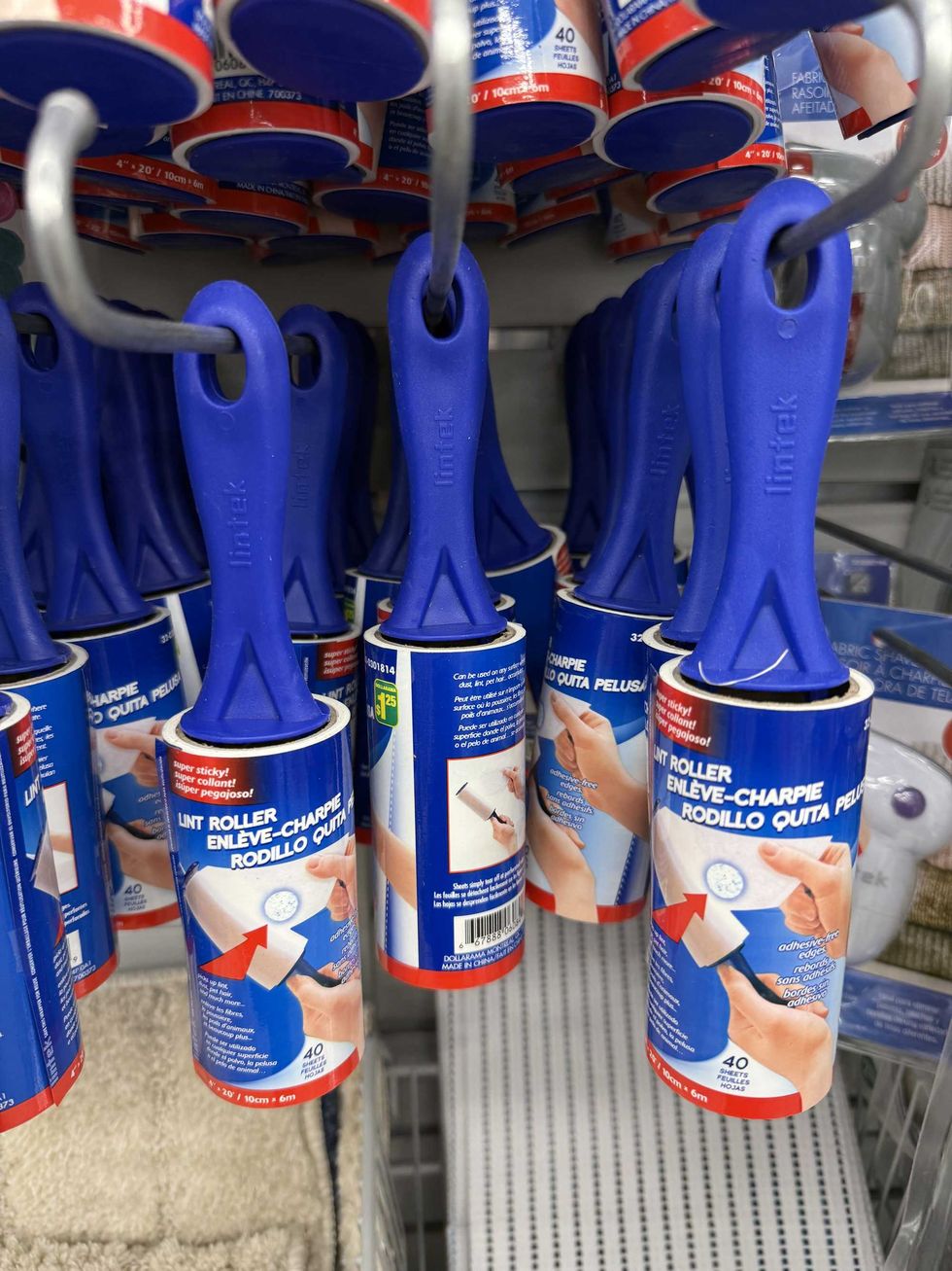 Blue, white and red lint rollers hanging on a store shelf.