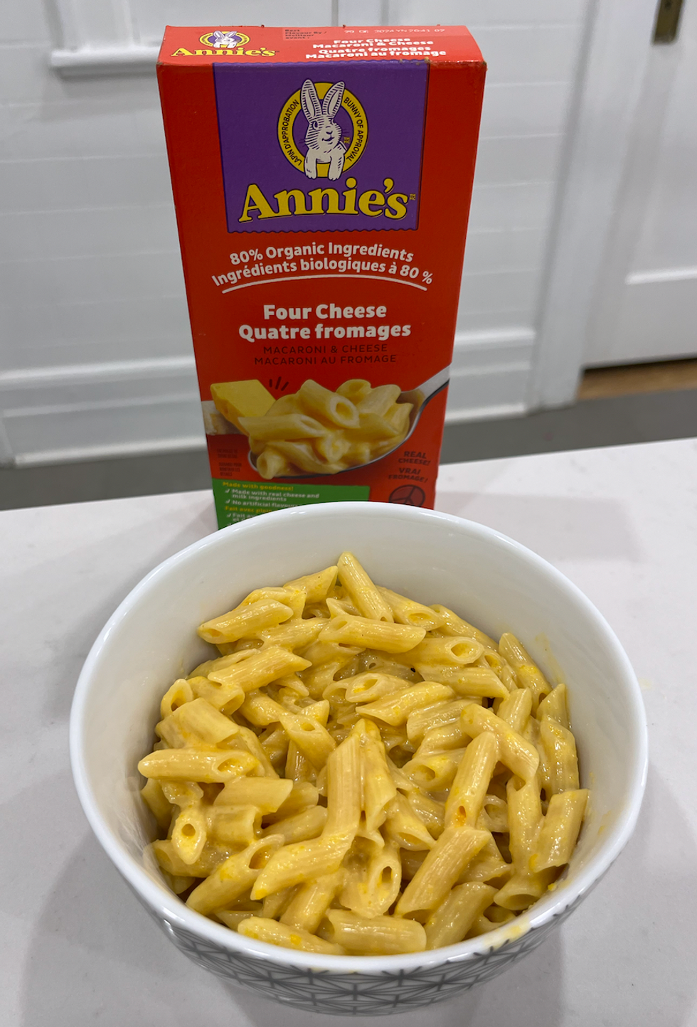 Bo\u00eete de macaronis au fromage de marque Annie's et un bol de macaronis pr\u00e9par\u00e9s.