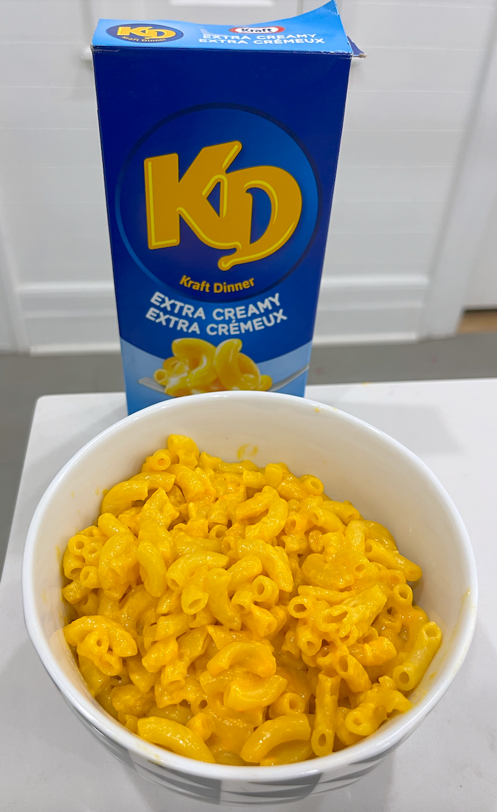 Bo\u00eete de macaronis au fromage de marque Kraft Dinner et un bol de macaronis pr\u00e9par\u00e9s.