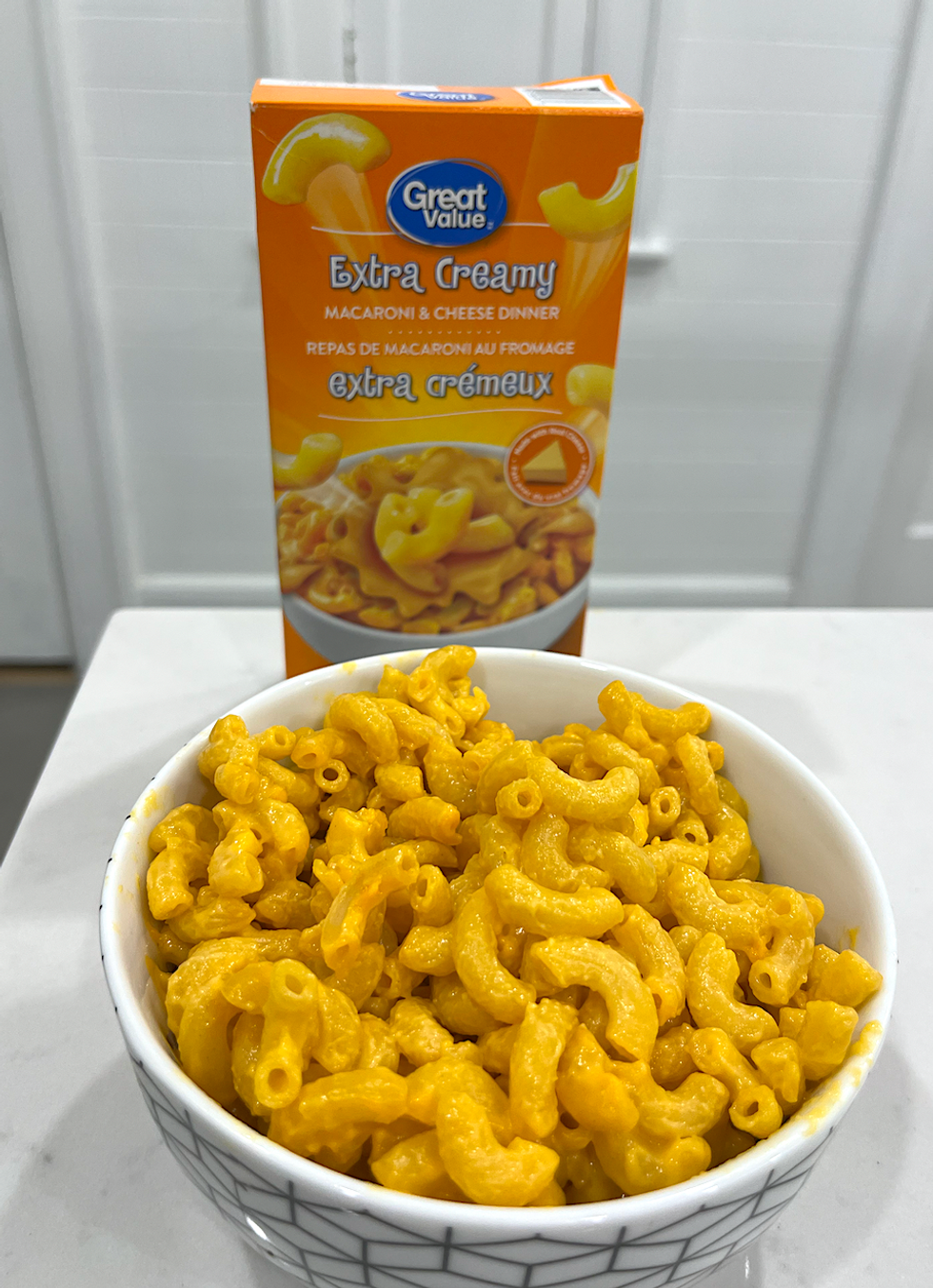 Bo\u00eete de macaronis au fromage de marque \u200bGreat Value et un bol de macaronis pr\u00e9par\u00e9s.