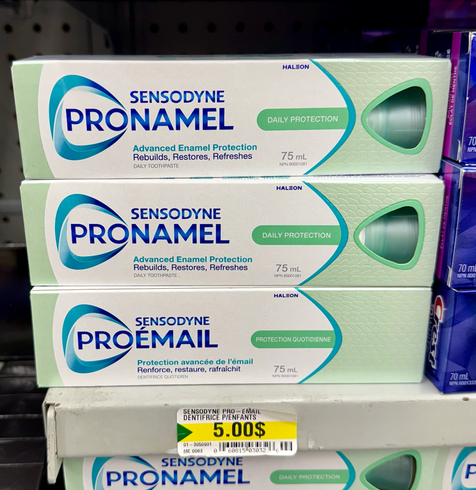 Bo\u00eetes de dentifrice Sensodyne Pro-\u00c9mail 75 ml align\u00e9es sur une tablette chez Dollarama.