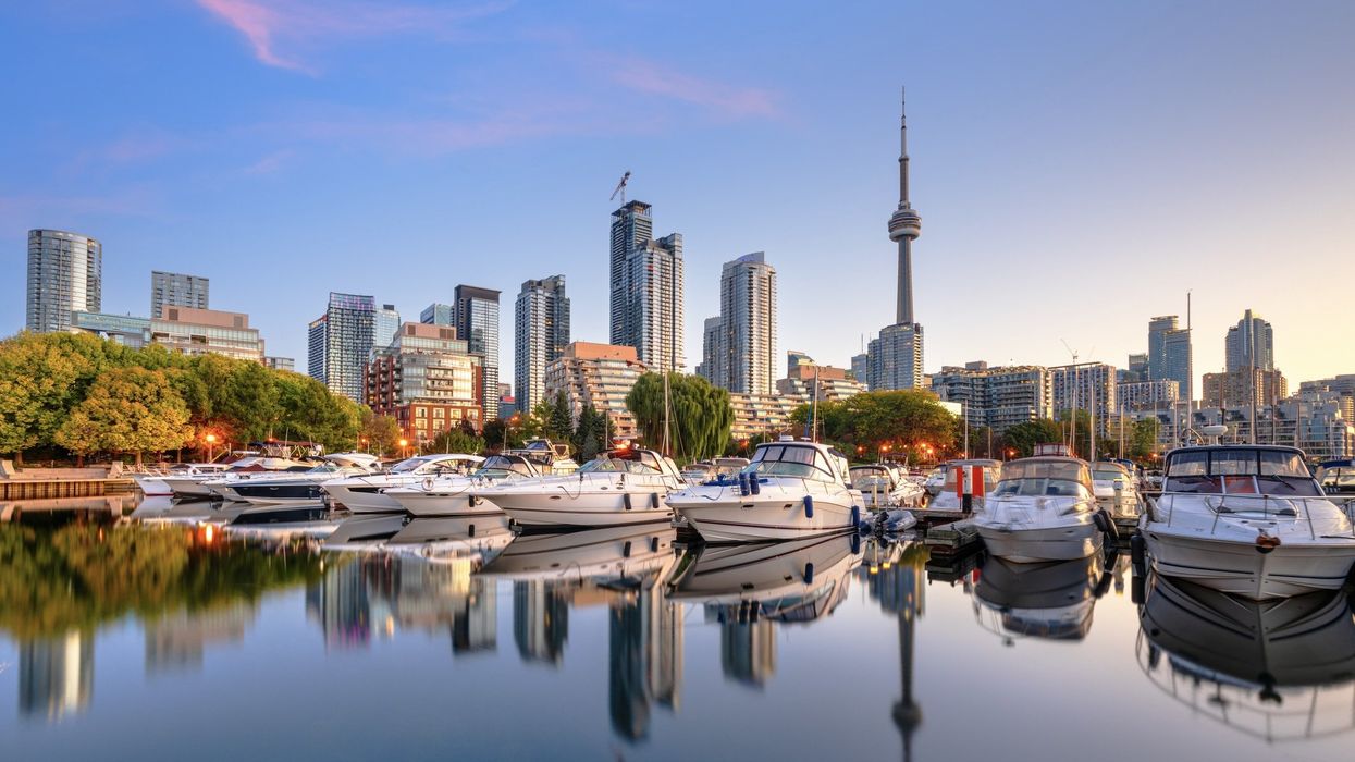 Boats in Toronto's Harbourfront at dawn with the CN Tower and skyline in the background.