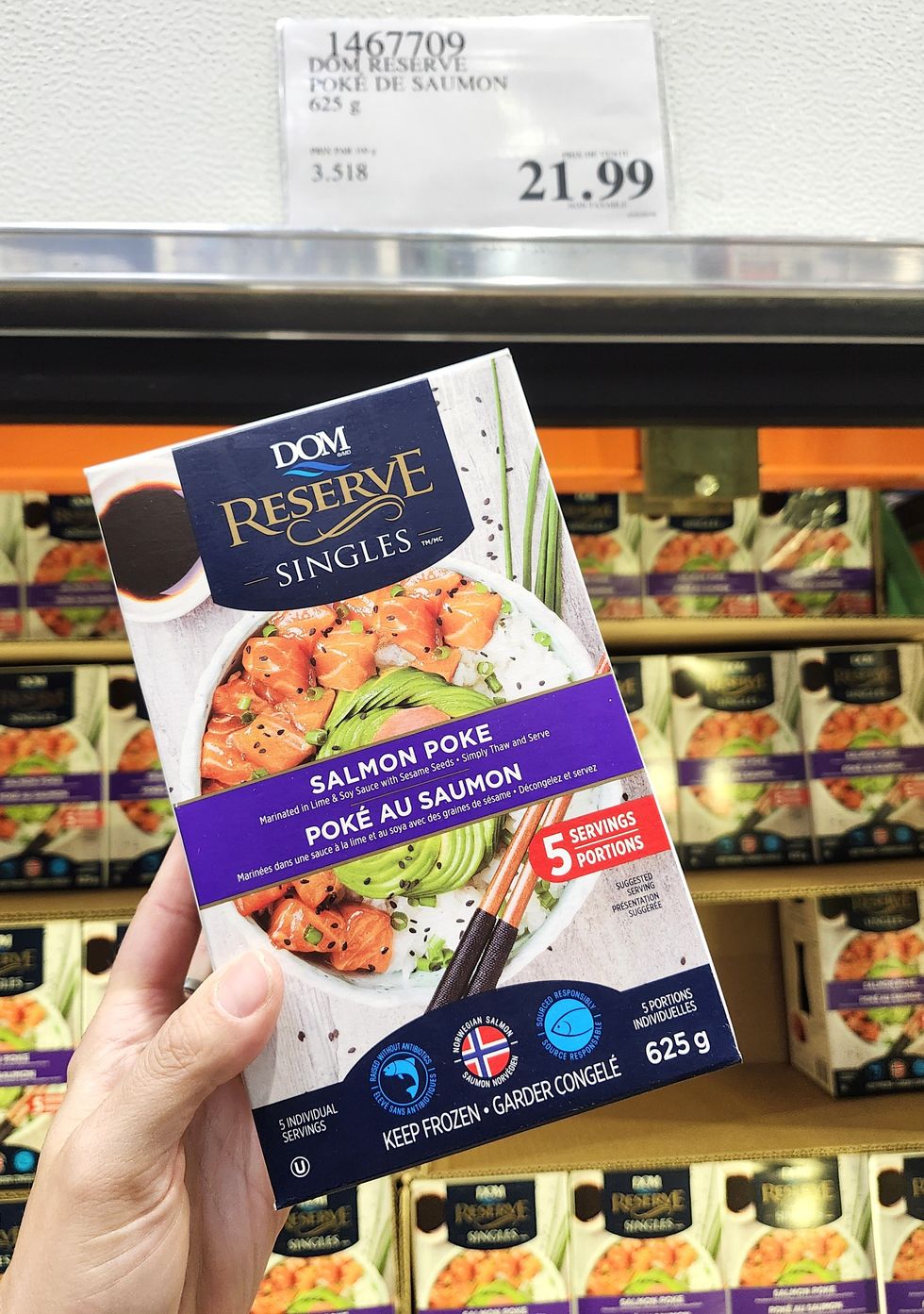 Boite de saumon en cubes congel\u00e9s dans une main.