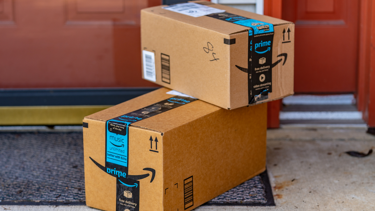 Boîtes d'Amazon Prime empilées par terre devant un domicile.