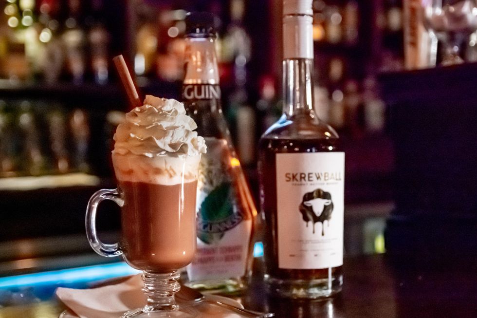 Boozy hot chocolate with whipped cream and cinnamon stick.
