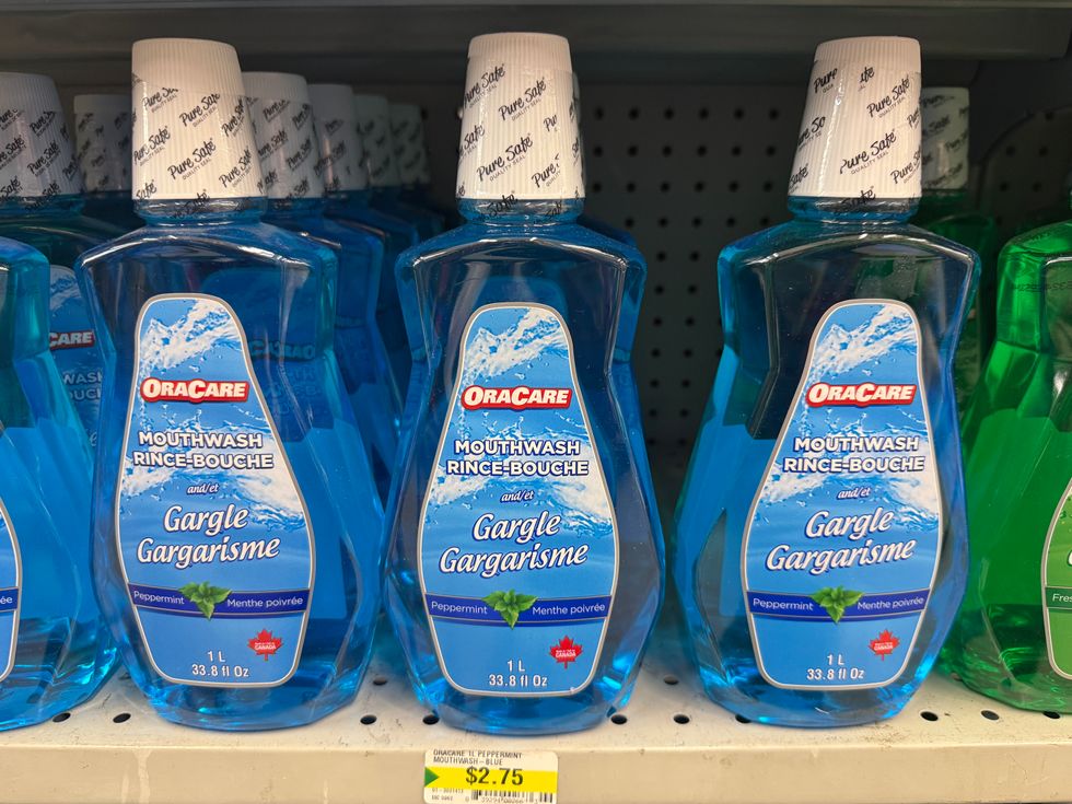 Bottles of blue liquid that say mouthwash on the front on a store shelf.