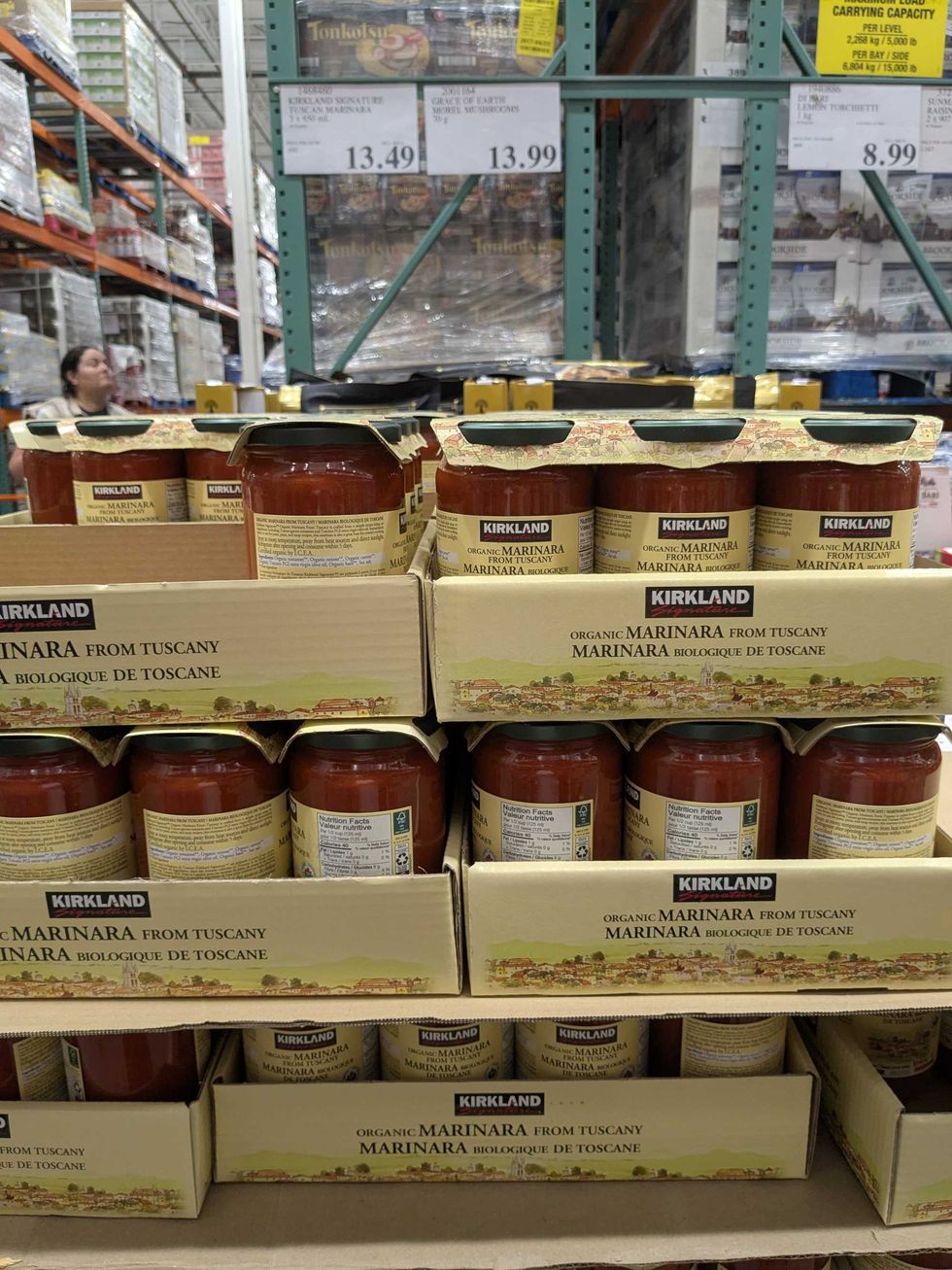 Boxes of Kirkland brand pasta sauce on a shelf at Costco