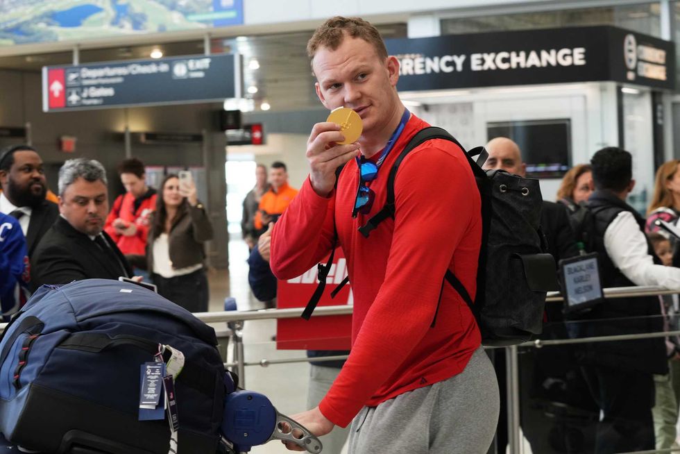 Brady Tkachuk shows off his Olympic goal medal at Miami International Airport.