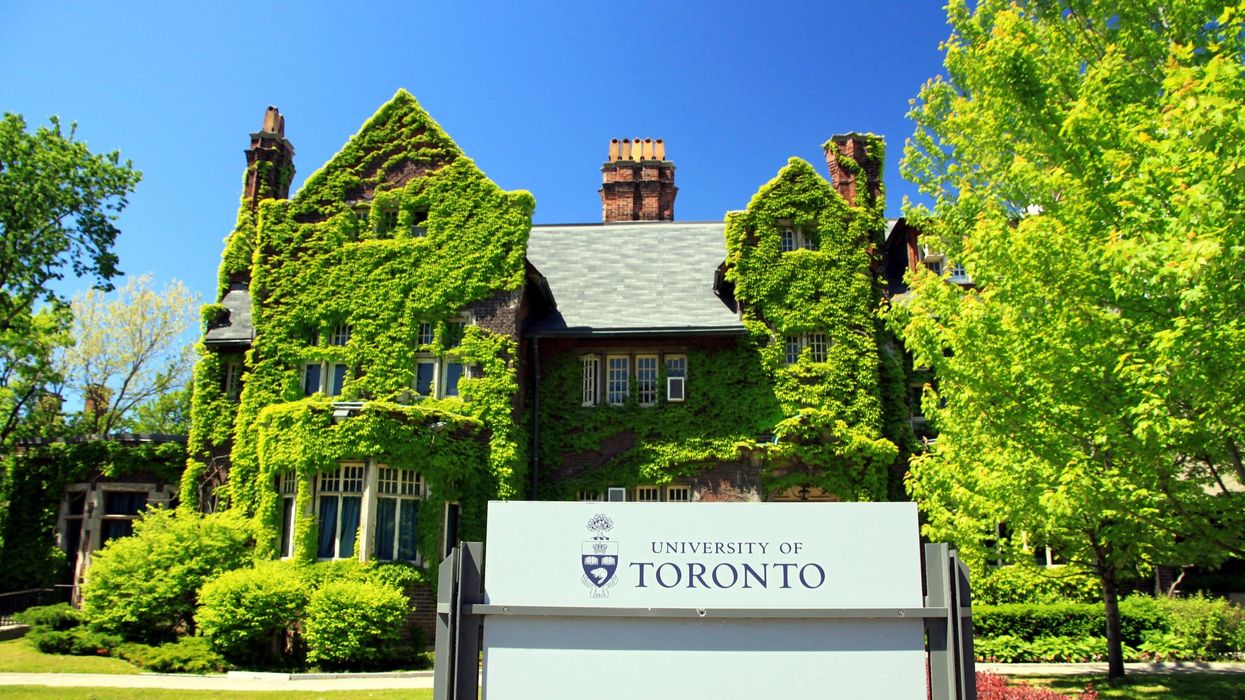 Brick building covered in greenery with a sign out front that says "University of Toronto."