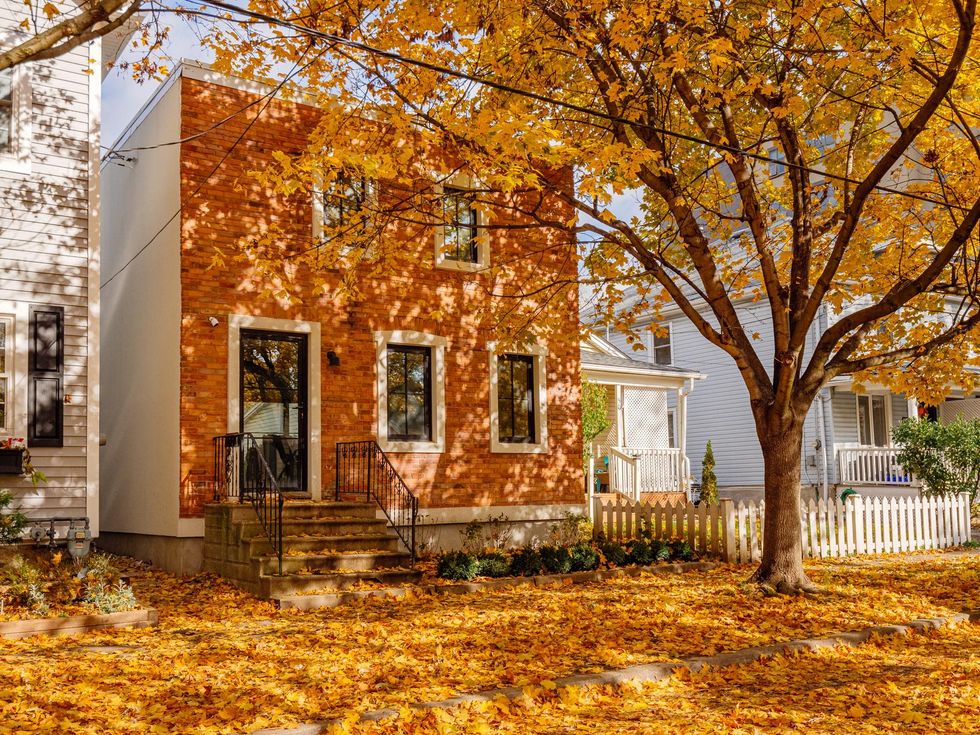 Brick home surrounded by fall leaves.