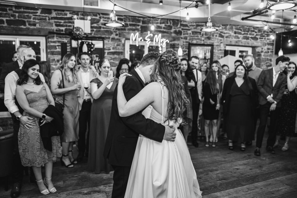 Bride and groom first dance inside a bar with exposed brick and twinkly lights.