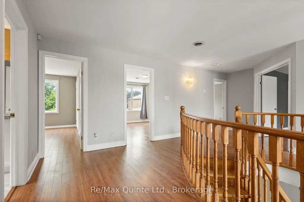 Bright hallway with wooden railing and multiple doorways.
