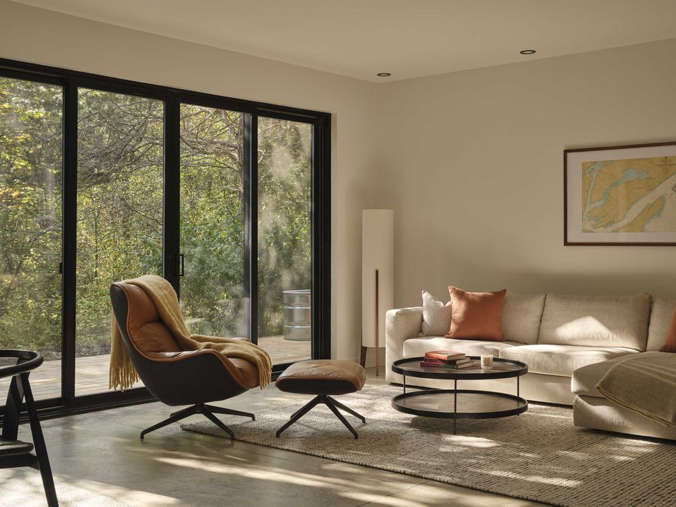 Bright living room with floor-to-ceiling windows, neutral decor, and forest views in a modern home.