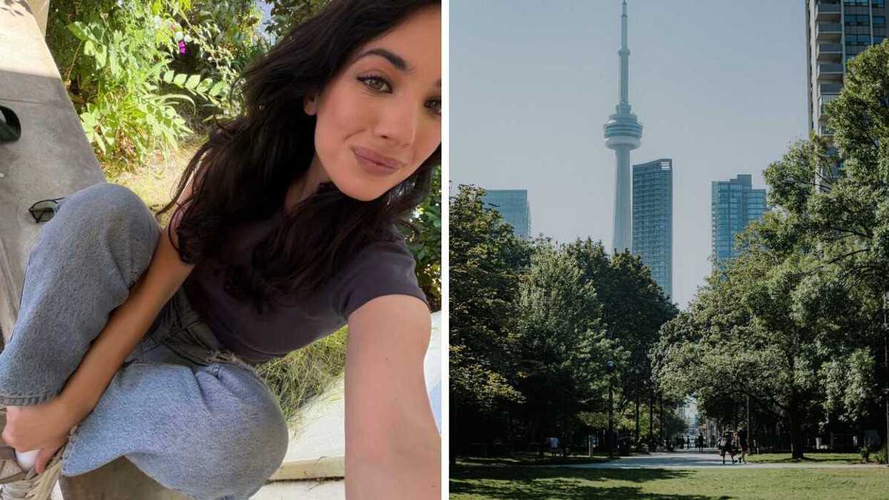 Brunette girl smiles and takes selfie with blue jeans and grey shirt. Right Toronto park with CN tower against blue sky on summer day.