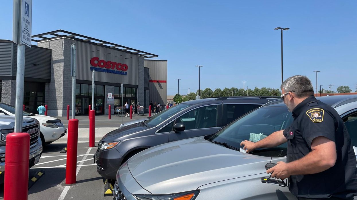 By-law officer issues parking ticket in a Costco parking lot.