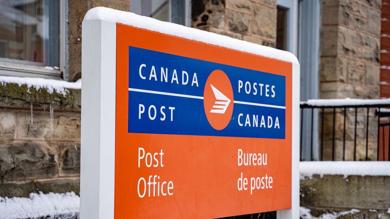 canada post sign covered in snow outside a post office