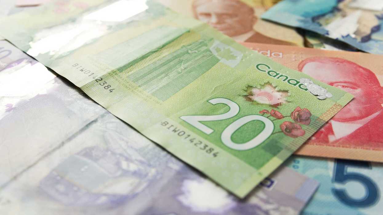 canadian $20 bill on top of $50, $5 and $100 bills
