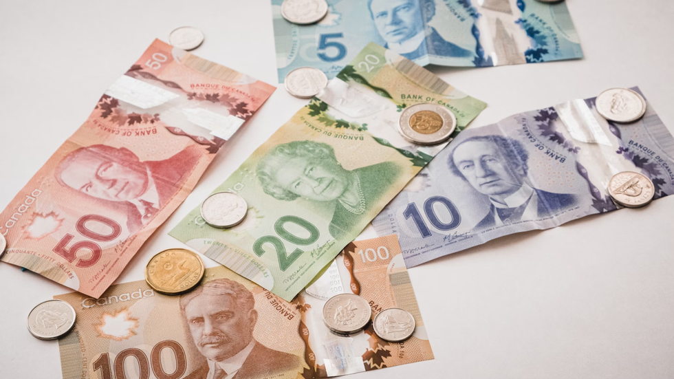 Canadian coins and bills are arranged on a white table.