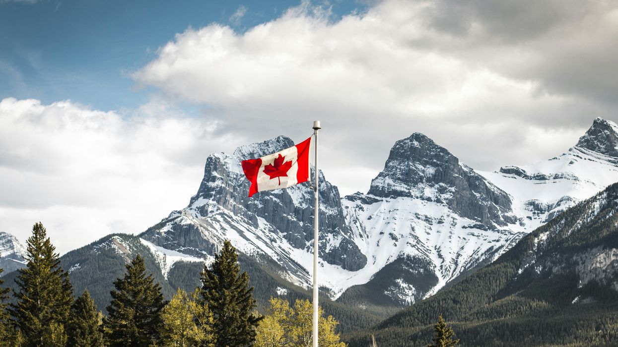 Canadian flag flies in front of snow-topped mountains in Canmore, Alberta.