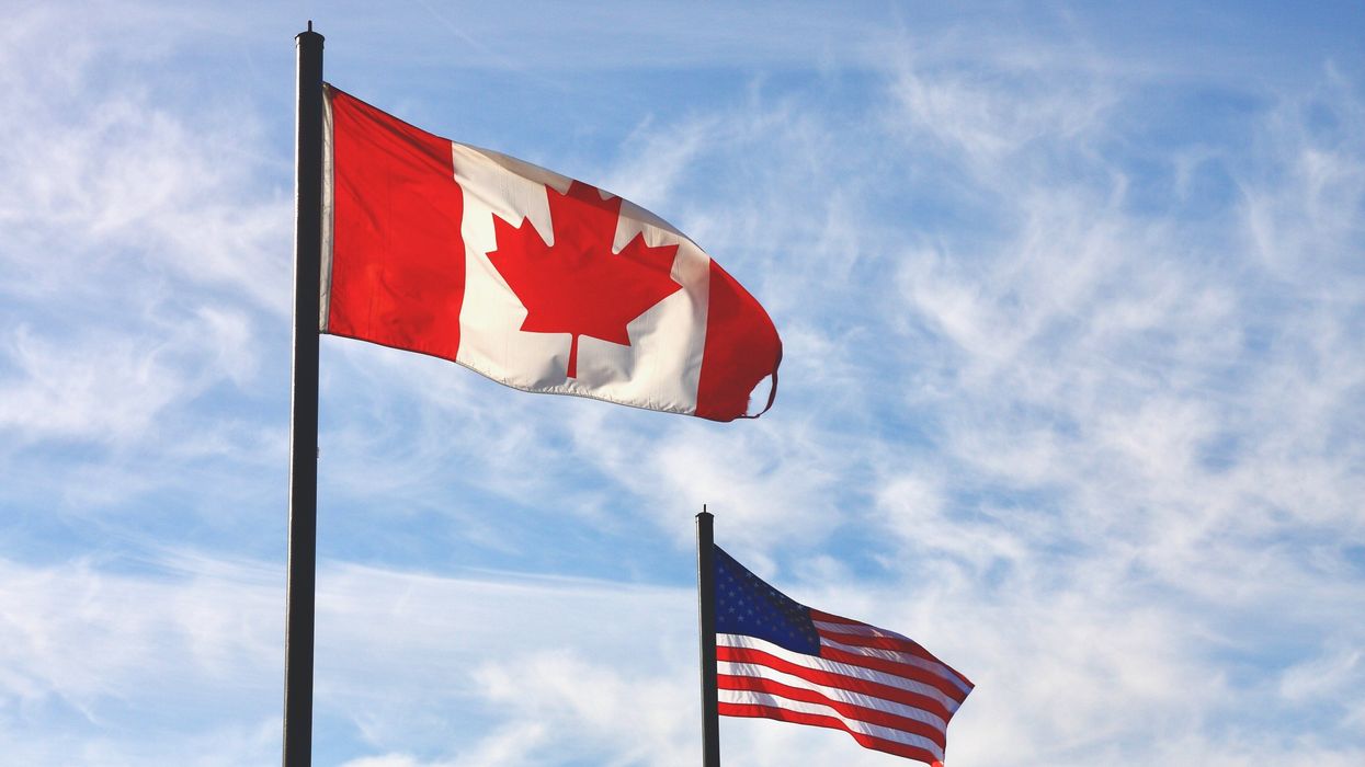Canadian flag waving in front of a smaller U.S. flag.