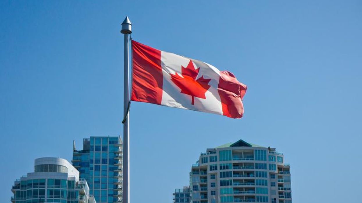 Canadian flag with skyscrapers in the background.