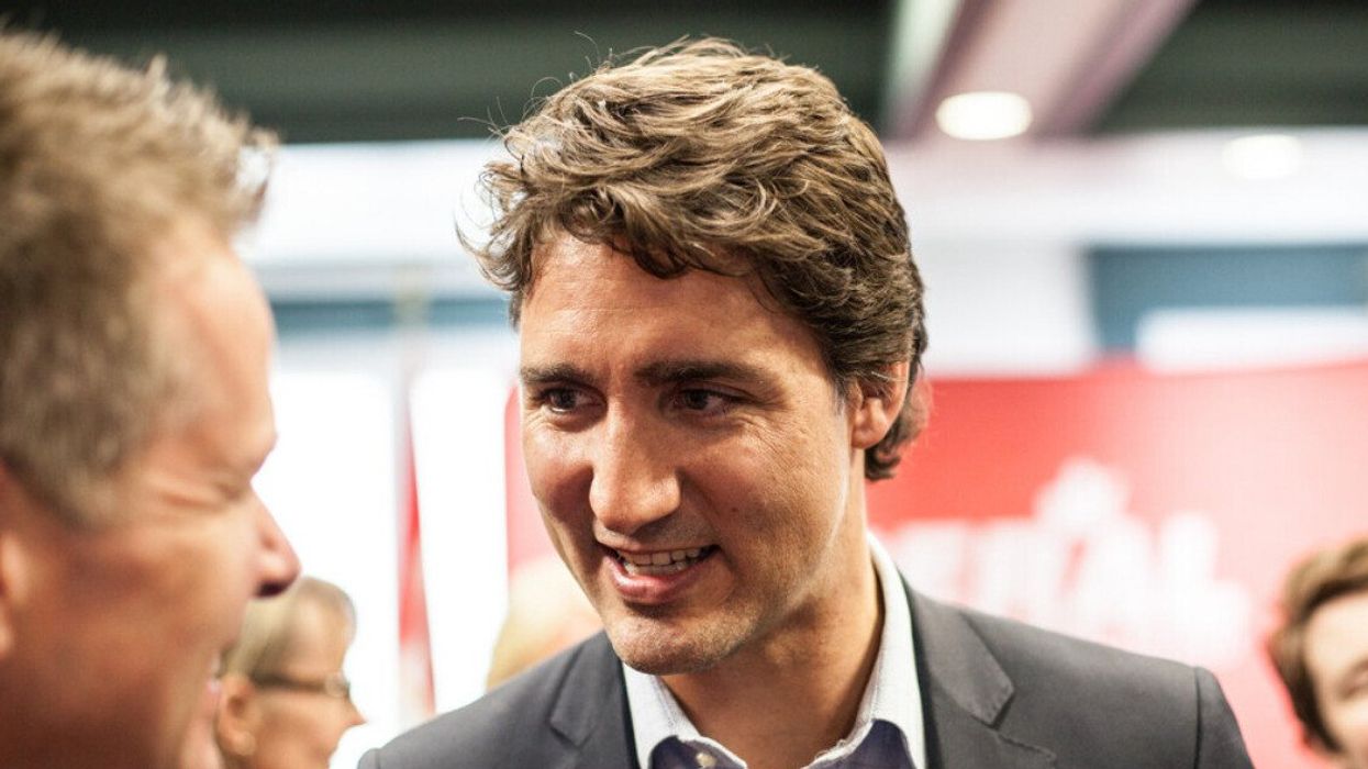 Canadian Prime Minister Justin Trudeau smiling as he talks to someone.