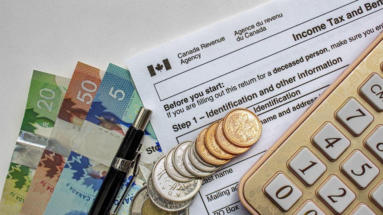 Canadian Tax Forms with money, calculator and a pen on a white table.