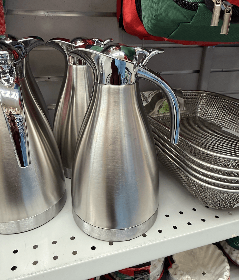 Carafes isothermes en acier inoxydable bross\u00e9 avec poign\u00e9e et bec verseur chrom\u00e9s sur une tablette du Dollarama.
