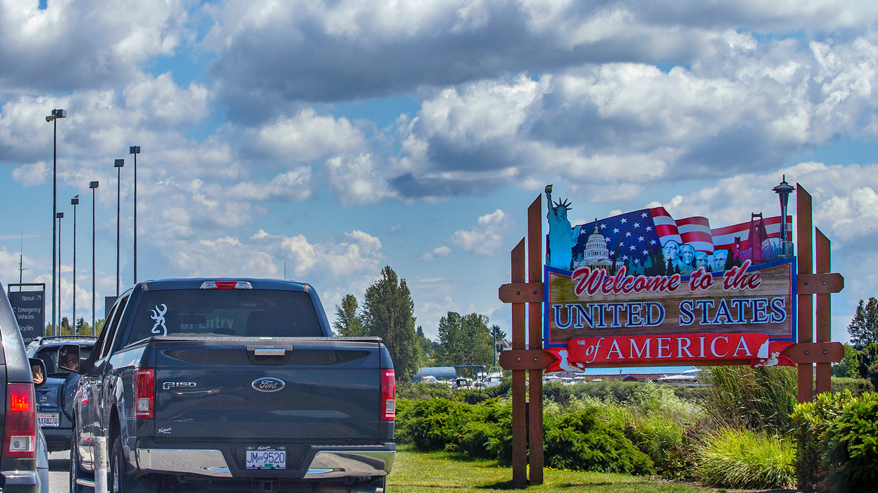 Cars line up at the Canada-U.S. border alongside a sign that reads "Welcome to the United States of America."