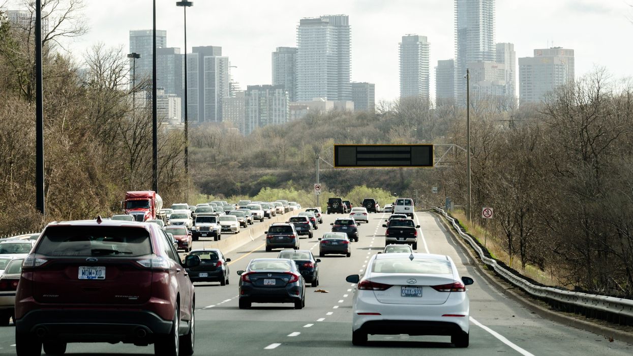 cars on a highway in toronto with the city skyline in the background
