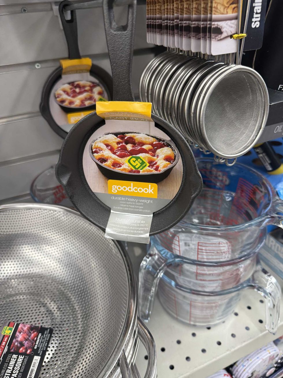 Cast iron pans hanging on a store shelf.