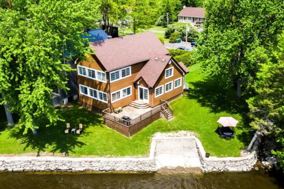 Chalet en bois sur la rivi\u00e8re des Outaouais avec un terrain gazonn\u00e9.