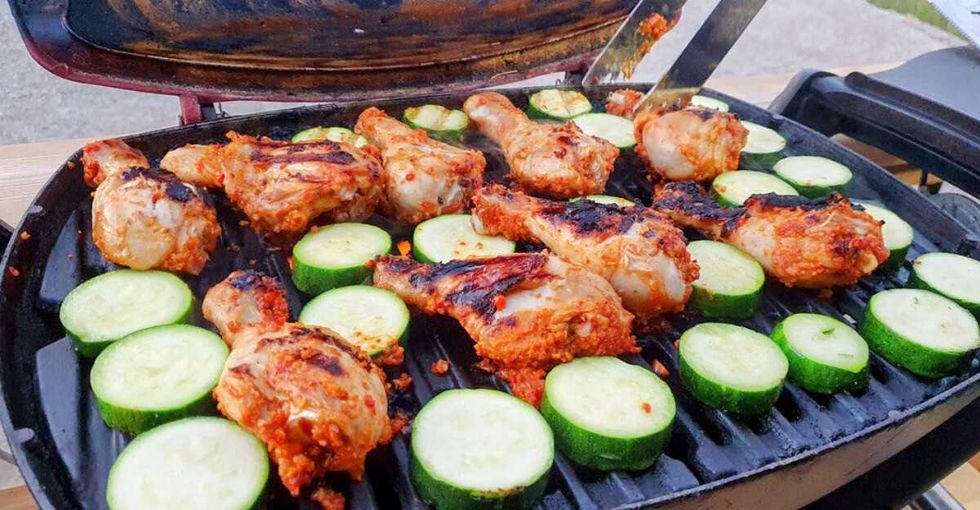 Chicken and zucchini grilling on an outdoor barbecue.