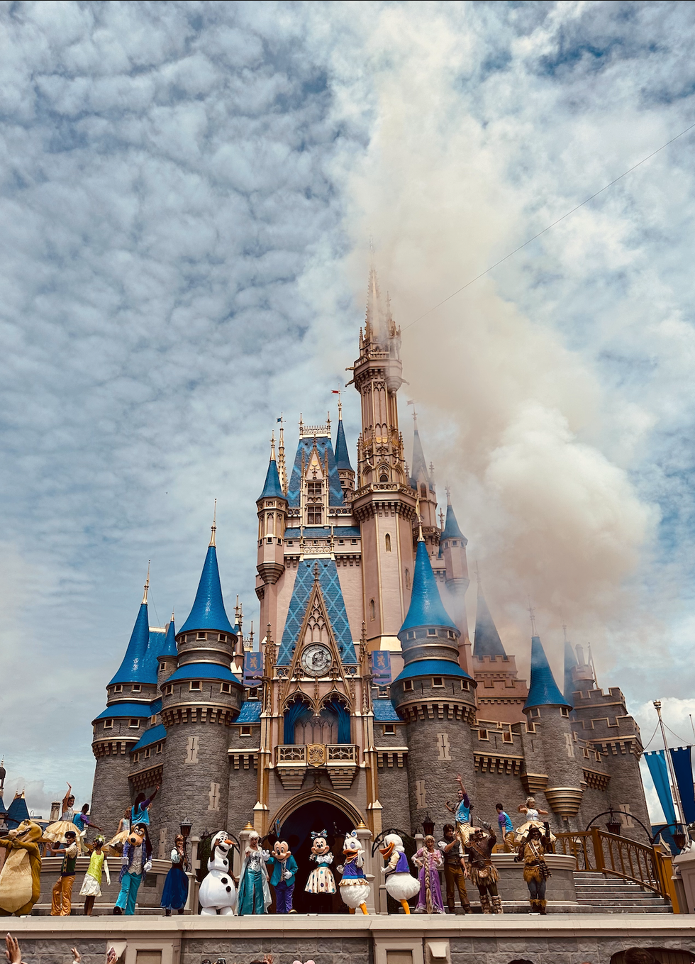 Cinderella's Castle at Disney World with characters performing on stage.