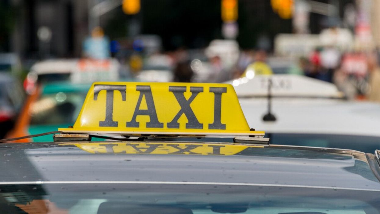 Close up of a taxi sign on top of a car in downtown Toronto traffic.