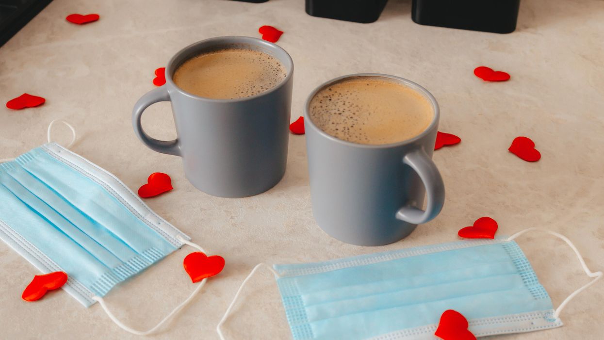 Coffee mugs on a table with face masks and hearts.