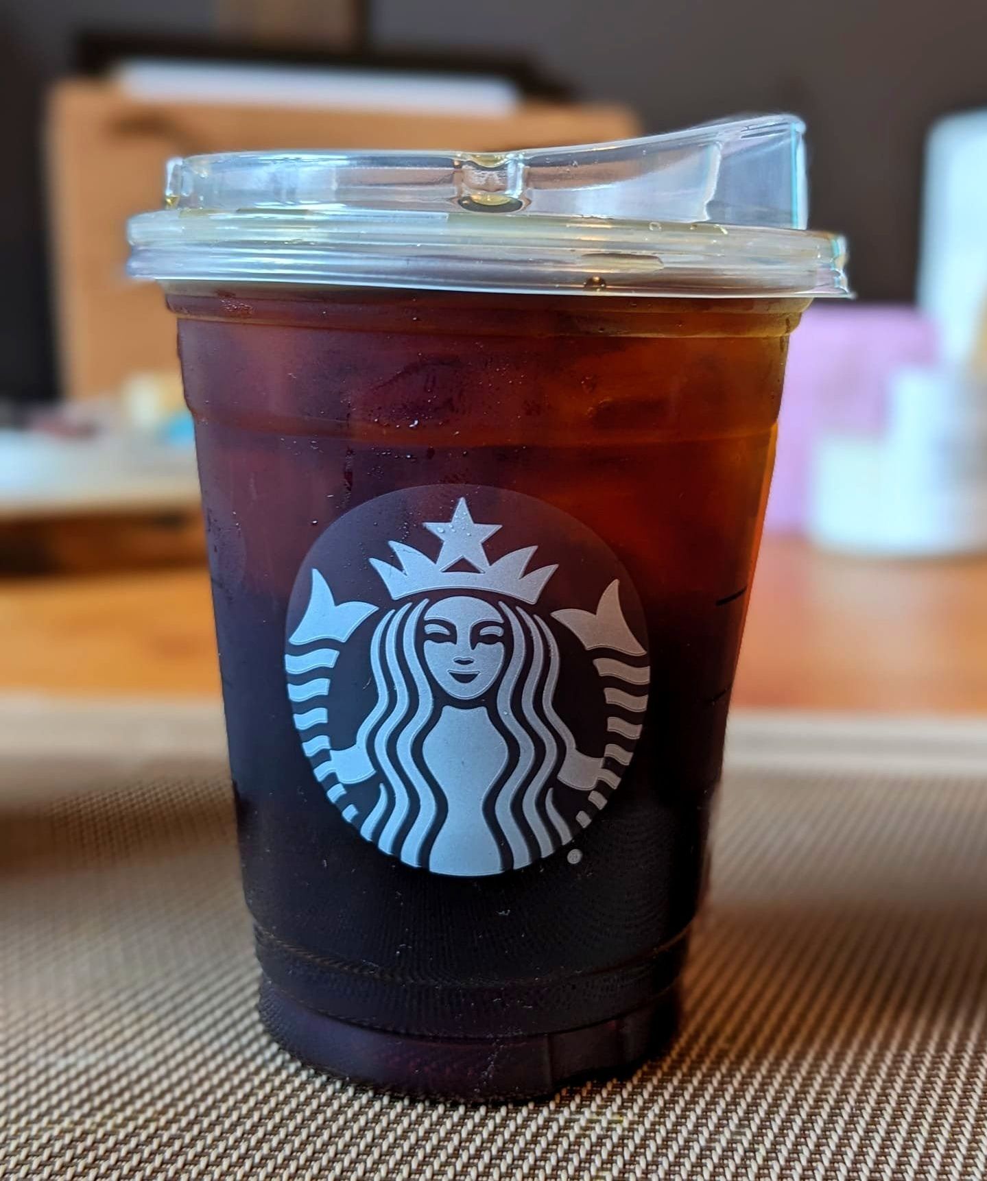 Cold brew from Starbucks in a clear plastic cup on a table.