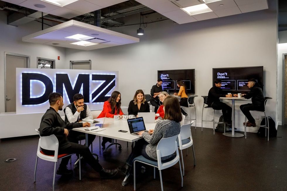 Colleagues work together around a desk at DMZ Toronto.