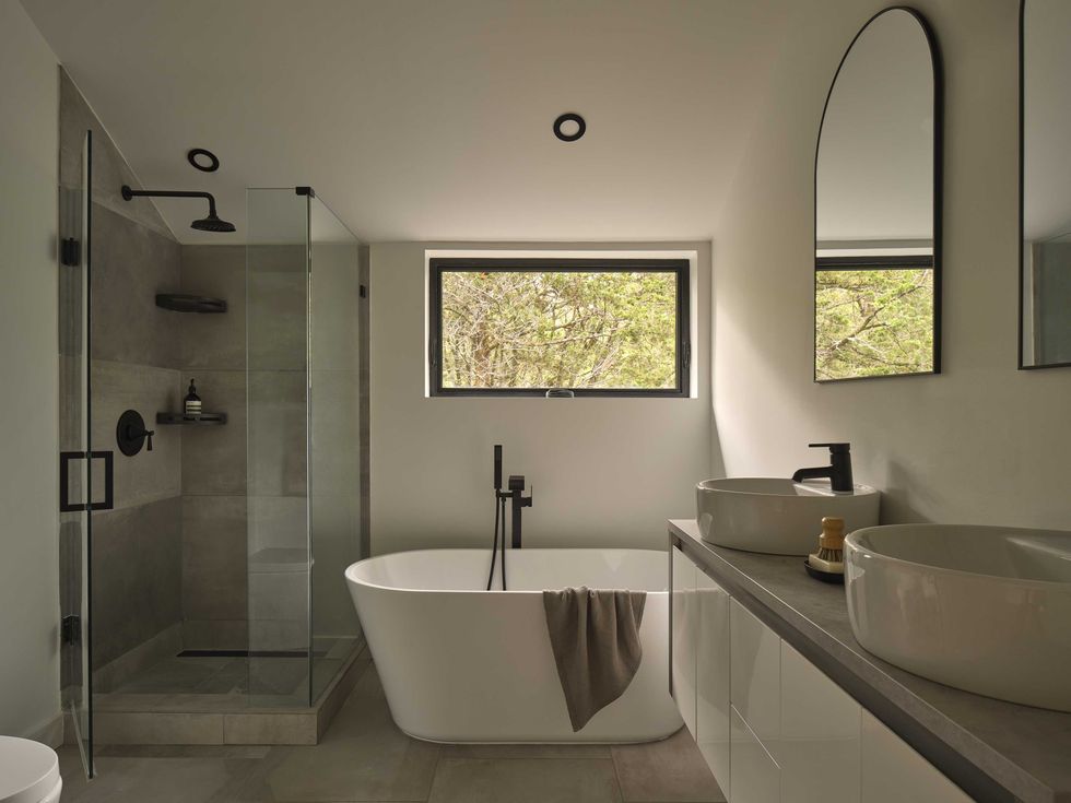 Contemporary bathroom featuring a freestanding tub, glass shower, and dual sinks with natural light.