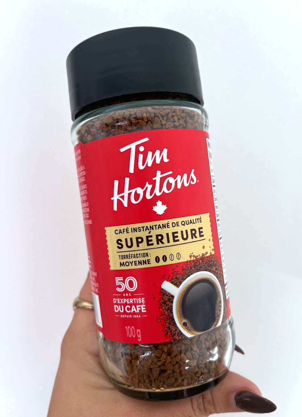 Contenant de caf\u00e9 instantan\u00e9 de la marque \u200bTim Hortons avec \u00e9tiquette rouge et la mention \u00ab Qualit\u00e9 sup\u00e9rieure \u00bb.