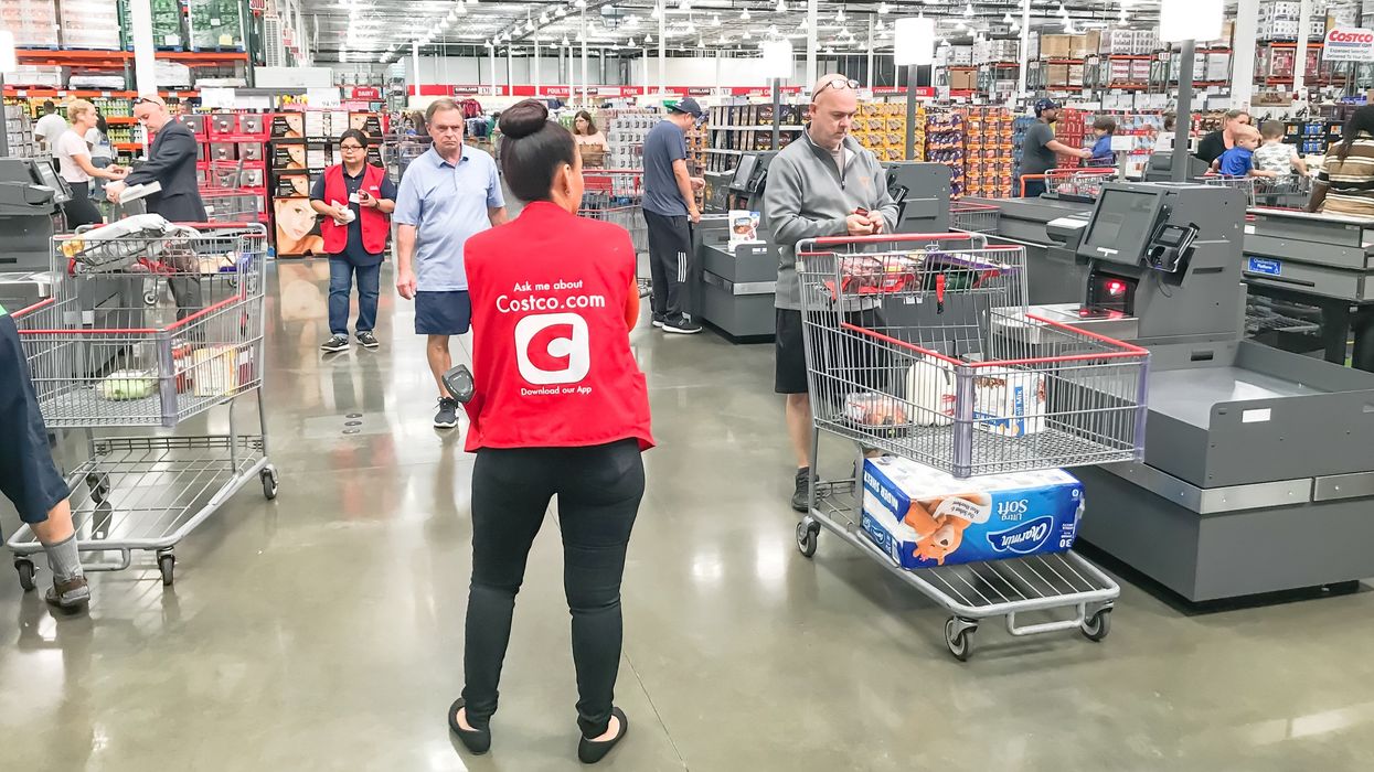 costco employee standing at the self-checkout in a warehouse location
