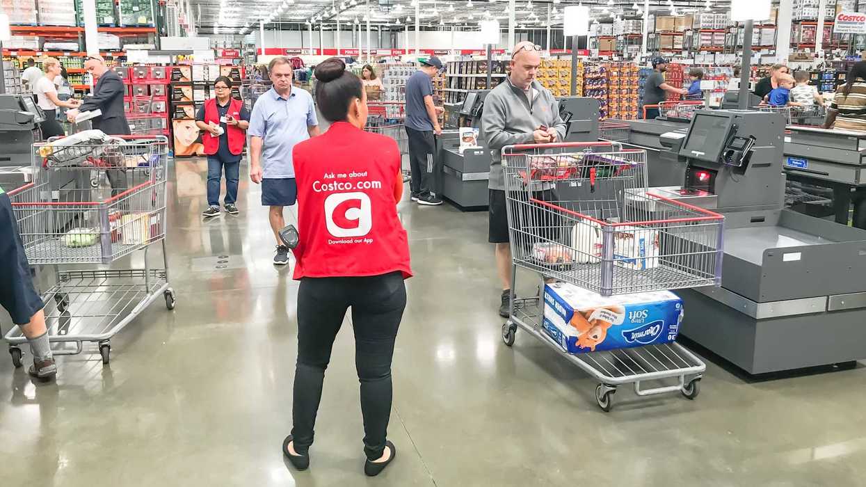 costco employee standing in front of customers at self checkout
